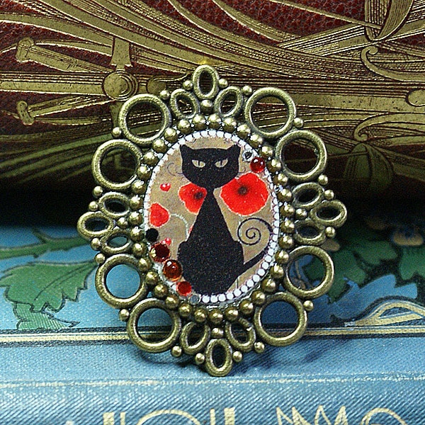 Broche en métal couleur bronze avec une image de chat noir