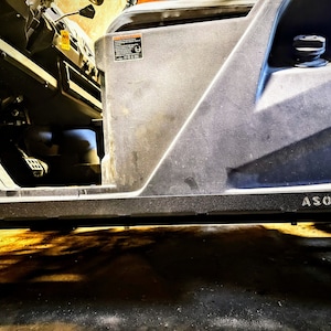 May include: Close-up of a black side step with the word "ASO" printed on it. The side step is attached to a gray vehicle.