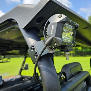 May include: A black off-road light bar mounted on a black metal roll cage. The light bar has a clear lens and a black housing with the word "Nilight" printed on it.