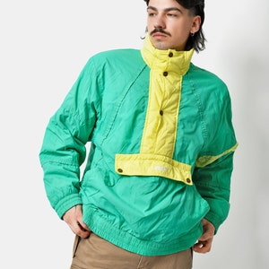以下が含まれることがあります： 襟が高く、ジッパーで閉めることができる緑と黄色のウィンドブレーカー。ジャケットには前面に大きなポケットと、ドローストリング付きのフードが付いている。