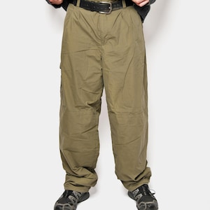 Może przedstawiać: Ciemnoszary sweter z niebieskimi paskami jest połączony z oliwkowymi spodniami cargo i czarnym paskiem. Strój uzupełniają czarno-szare buty sportowe, tworząc swobodny, codzienny wygląd.