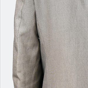May include: A close-up of the sleeve of a gray blazer. The fabric has a subtle texture and a single seam down the side.