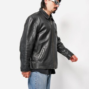 以下が含まれることがあります： ジッパー留めとスタンドカラーの黒い革のジャケット。ジャケットには前面にポケットが2つとウエストにベルトが付いています。
