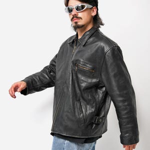 以下が含まれることがあります： ジッパー留めとスタンドカラーのブラックレザージャケット。ジャケットには前面にポケットが2つ、左袖にジッパー付きポケットが1つある。