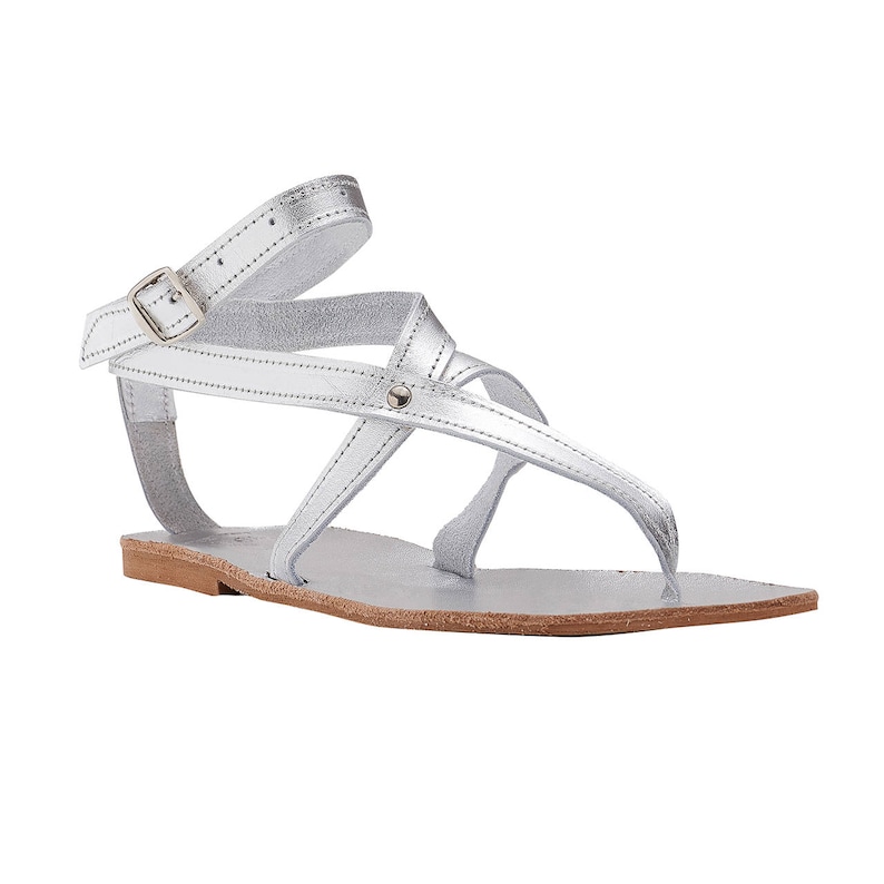 May include: Silver leather sandals with a buckle closure and multiple straps. The sandals have a flat sole.