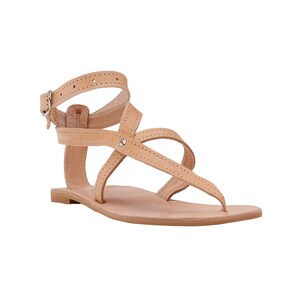 May include: Tan leather sandals with criss-cross straps and a buckle closure.