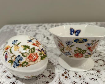 Könnte beinhalten: Eine weiße Porzellan-Schmuckdose in Ei-Form mit einem Blumenmuster und einem Schmetterling. Eine weiße Porzellan-Schale mit einem Blumenmuster und einem Schmetterling ist ebenfalls abgebildet.