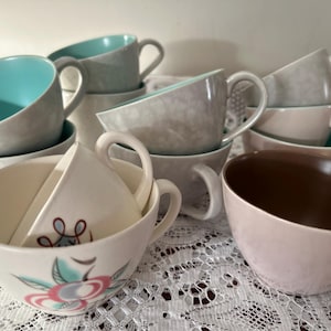 Puede incluir: Un juego de nueve tazas de té de cerámica en varios tonos de azul, gris y marrón. Las tazas tienen un diseño floral y están apiladas unas encima de otras.