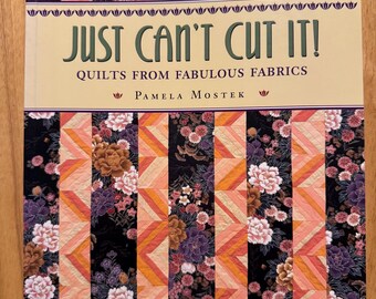 以下が含まれることがあります： パメラ・モステク著「Just Can't Cut It! Quilts from Fabulous Fabrics」というタイトルの本。表紙は、ピンク、オレンジ、黒の色合いの花柄のパッチワークデザインです。そのパッチワークプレイスからの本です。