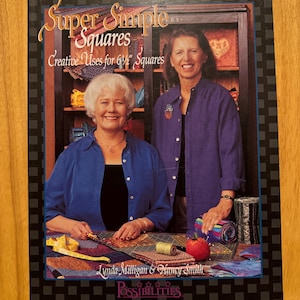 May include: Book cover featuring two women with short hair, smiling, and holding fabric squares. The book title is "Super Simple Squares: Creative Uses for 6 1/2" Squares" and the authors are Lynda Milligan and Nancy Smith.