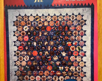 以下が含まれることがあります： 赤い背景に「Look What I See Quilts」というタイトルが書かれた本の表紙。表紙には、青い背景にさまざまなカラフルなデザインが施されたキルトが描かれている。