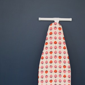 May include: A white ironing board cover with a pink and red strawberry pattern.