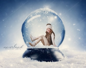 May include: A young girl wearing a white hat and a brown vest sits inside a snow globe. The snow globe is on a white snowy surface with a blue background.