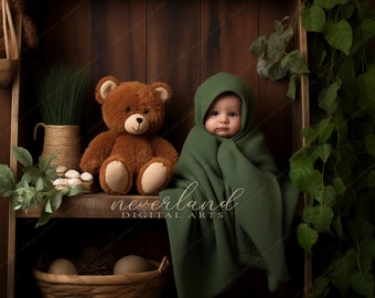 May include: A baby wrapped in a dark green blanket with a hood sits next to a brown teddy bear. The background features a wooden shelf with decorative items and a wooden wall. The image has a warm, inviting feel.