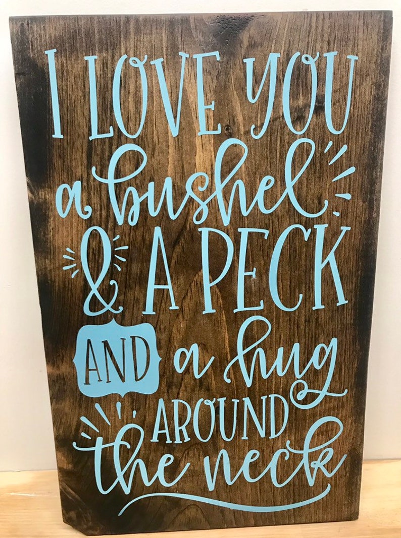 May include: Wooden sign with the text "I love you a bushel & a peck and a hug around the neck" in light blue lettering.