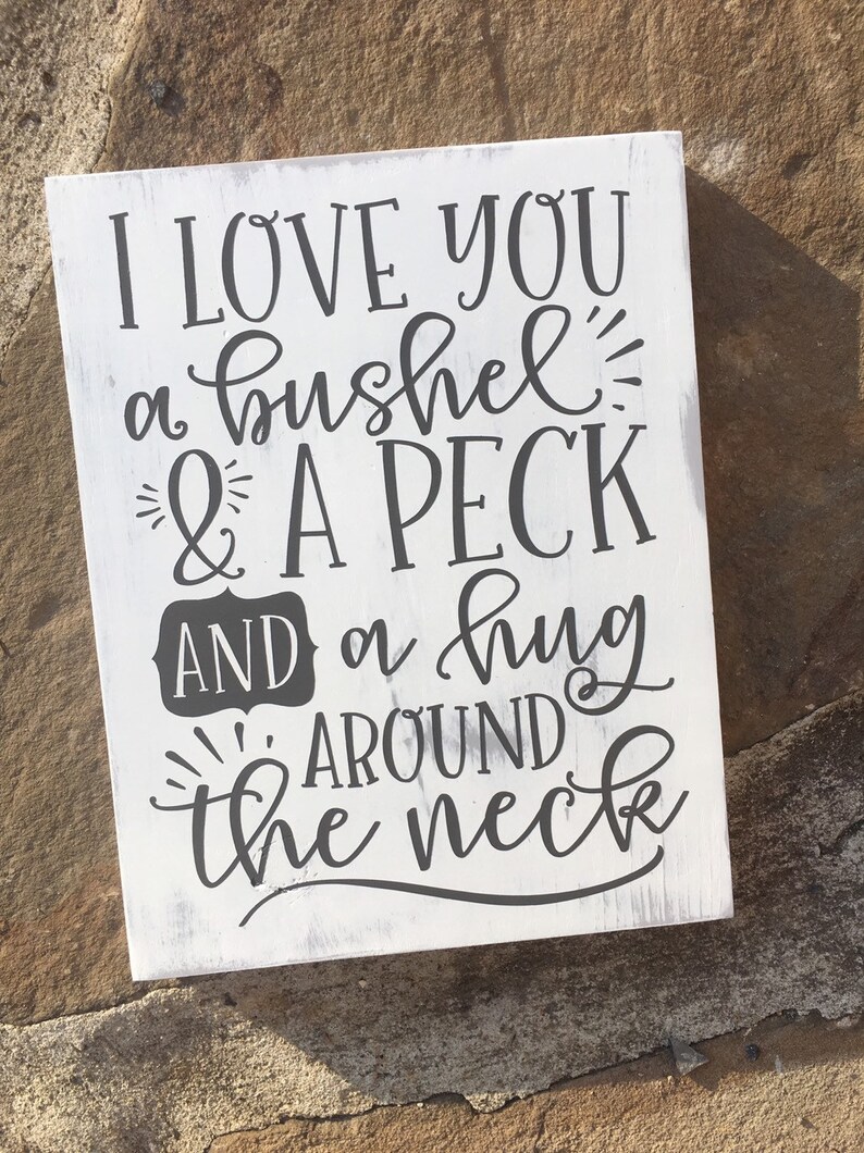May include: White wooden sign with black text that reads "I love you a bushel & a peck and a hug around the neck."