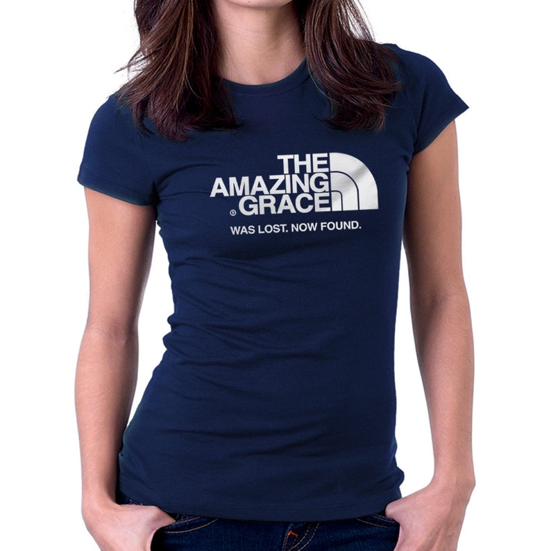 Puede incluir: Una camiseta azul marino con un gr&aacute;fico blanco de una cordillera y el texto "THE AMAZING GRACE WAS LOST. NOW FOUND."