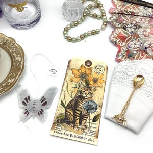 Tee Geschenk. Vintage Carta Postale Katzenpostkarte, schwarzer Tee und Rosen-Schmetterlings-Tee, bestickte Serviette und vergoldeter Teelöffel