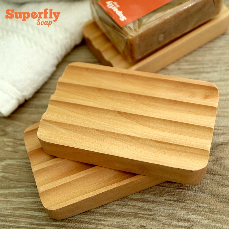 Puede incluir: Dos jaboneras de madera con un dise&ntilde;o acanalado. Las jaboneras est&aacute;n apiladas una encima de la otra. La jabonera superior es ligeramente m&aacute;s grande que la inferior.