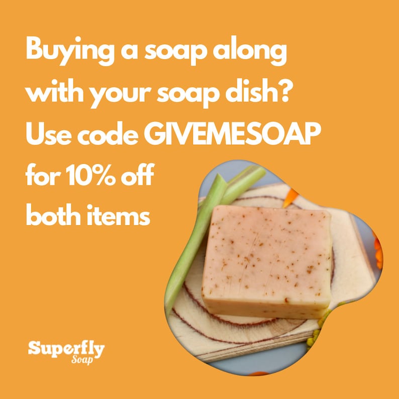 May include: A light pink bar of soap with brown flecks sits on a wooden soap dish. The soap is surrounded by green stems and yellow flowers. The text "Buying a soap along with your soap dish? Use code GIVEMESOAP for 10% off both items" is displayed in white text on a bright orange background. The text "Superfly Soap" is displayed in white text on a black background at the bottom of the image.
