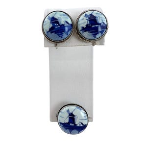 以下が含まれることがあります： オランダのデルフト焼きのヴィンテージイヤリングとブローチのセット。各作品は、家と木のある風車をモチーフにした青と白の磁器のデザインが施されています。