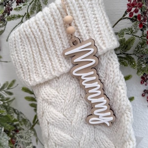 May include: White knitted stocking with a wooden tag that says "Mummy" in white lettering.