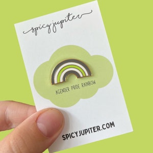 Peut inclure: Une épingle en émail arc-en-ciel vert, blanc et noir avec le texte "Agender Pride Rainbow" et le site Web "spicyjupiter.com".