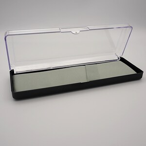 May include: A black plastic case with a clear plastic lid. The case has a gray felt lining.