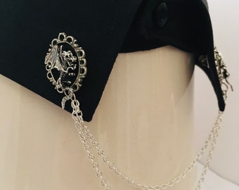 May include: A pair of silver collar clips with a dragon design and a chain. The clips are attached to a black shirt collar.