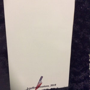 May include: A white card with a small, red-stained knife illustration and the text "LowKee Creations, 2018" in black.