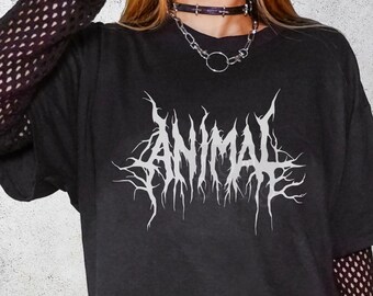 Può includere: T-shirt nera con la scritta "ANIMAL" in bianco, con caratteri gotici stilizzati. La maglietta è indossata con una maglia a maniche lunghe a rete nera sotto. Sono visibili anche un choker e una collana.