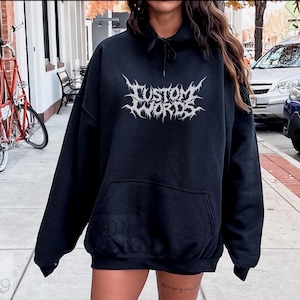 May include: Black hooded sweatshirt with a silver graphic that says "CUSTOM WORDS" in a metal band style font.