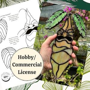 Könnte beinhalten: Ein Kunstwerk aus Buntglas, das eine cartoonartige Figur mit einem gelben Körper, grünen Blättern und schwarzen Umrissen darstellt. Die Figur hat einen mürrischen Gesichtsausdruck mit schwarzen Augen, einer schwarzen Nase und einem schwarzen Mund. Das Kunstwerk wird in einer Hand vor einem grünen, blättrigen Hintergrund gehalten. Der Text "Hobby/Commercial License" ist in der linken unteren Ecke des Bildes sichtbar.