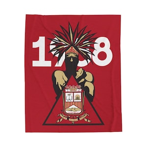 Puede incluir: Manta roja con un "1908" blanco impreso en ella. Una silueta negra de una persona con un tocado está en el centro de la manta. La persona sostiene un escudo con el texto "NAK" y un escudo de armas con un libro, una pirámide y una mano sosteniendo un sol. El escudo está rodeado por un triángulo con el texto "NU ALPHA KAPPA" impreso en él.