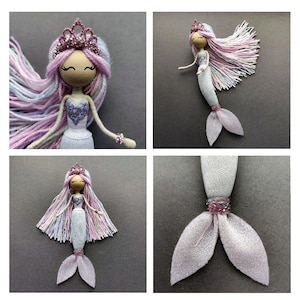 May include: A handmade doll with a pink and white yarn wig, a purple bodice, and a white and silver glitter mermaid tail. The doll is wearing a pink crown.