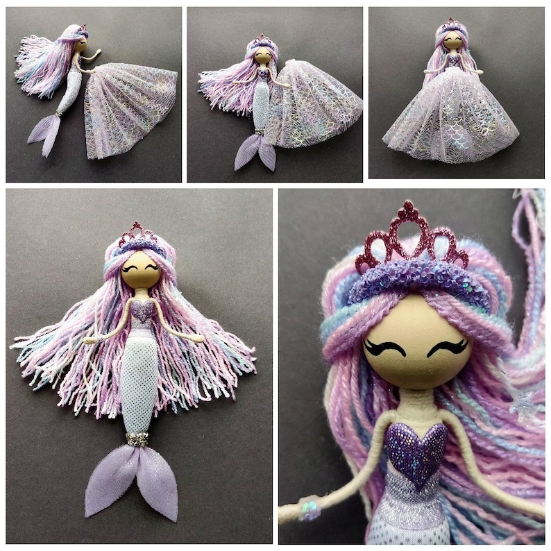 May include: A handmade mermaid doll with a purple and pink yarn hair, a sparkly purple bodice, and a white and purple tail. The doll is wearing a pink crown and has a painted face.