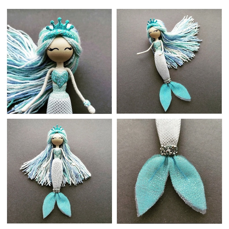 May include: A handmade mermaid doll with a blue and white yarn hair, a blue glitter crown, and a blue glitter tail. The doll is made of wood and has a white mesh bodice.