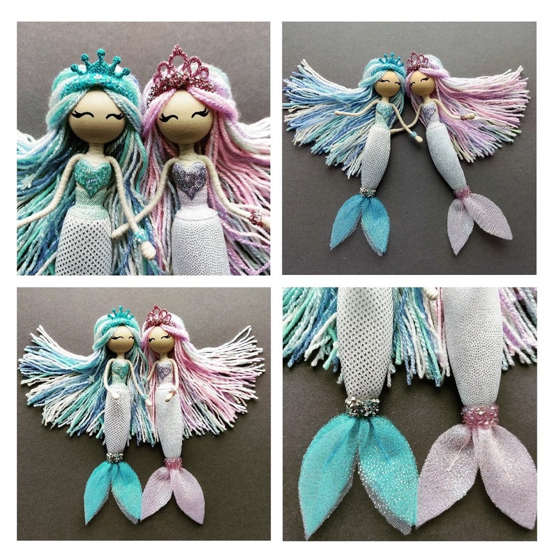 May include: Two yarn mermaid dolls with pink and blue yarn hair, wearing crowns and white mesh skirts with tulle tails. The dolls are holding hands.