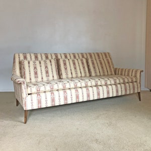 May include: A vintage striped sofa with a beige and brown patterned fabric. The sofa has three cushions and wooden legs.