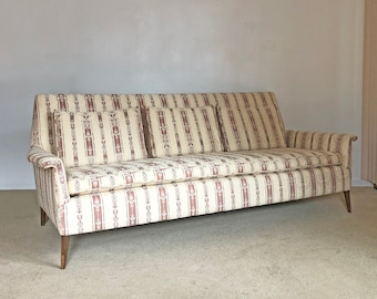 May include: A vintage striped sofa with a beige and brown patterned fabric. The sofa has three cushions and wooden legs.