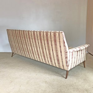 May include: A striped fabric sofa with wooden legs. The sofa is in a light beige and brown color scheme.