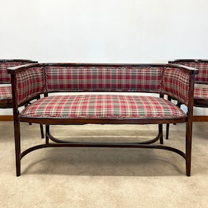 May include: A set of three chairs with a plaid fabric upholstery. The chairs have a curved back and wooden frame. The chairs are arranged in a row with the middle chair being a longer sofa.