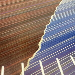 May include: Abstract art piece with a color gradient. The left side features a brown and red color scheme with horizontal lines. The right side has a blue and purple color scheme with white lines. The two sides are separated by a wavy, off-white line.