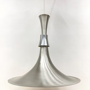 May include: A brushed silver pendant light fixture with a flared, conical shade. The light has a slender, hourglass-shaped central body and is suspended from a white ceiling mount. The fixture is a modern design.
