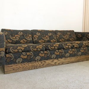 May include: A brown and black patterned sofa with a wooden base. The sofa has a tufted design and is in a mid-century modern style.