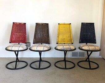 May include: Four mid-century modern chairs with black metal frames and woven cane backs. The chairs have red, brown, yellow, and black cane backs and patterned fabric seats.