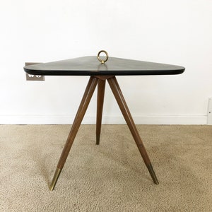 May include: A triangular black side table with a brass ring on top and three wooden legs with brass tips.