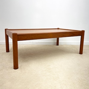 May include: A rectangular wooden coffee table with a warm brown finish. The table has a simple design with four sturdy, cylindrical legs and a flat top. The table measures approximately 48 inches long, 24 inches wide, and 16 inches high.
