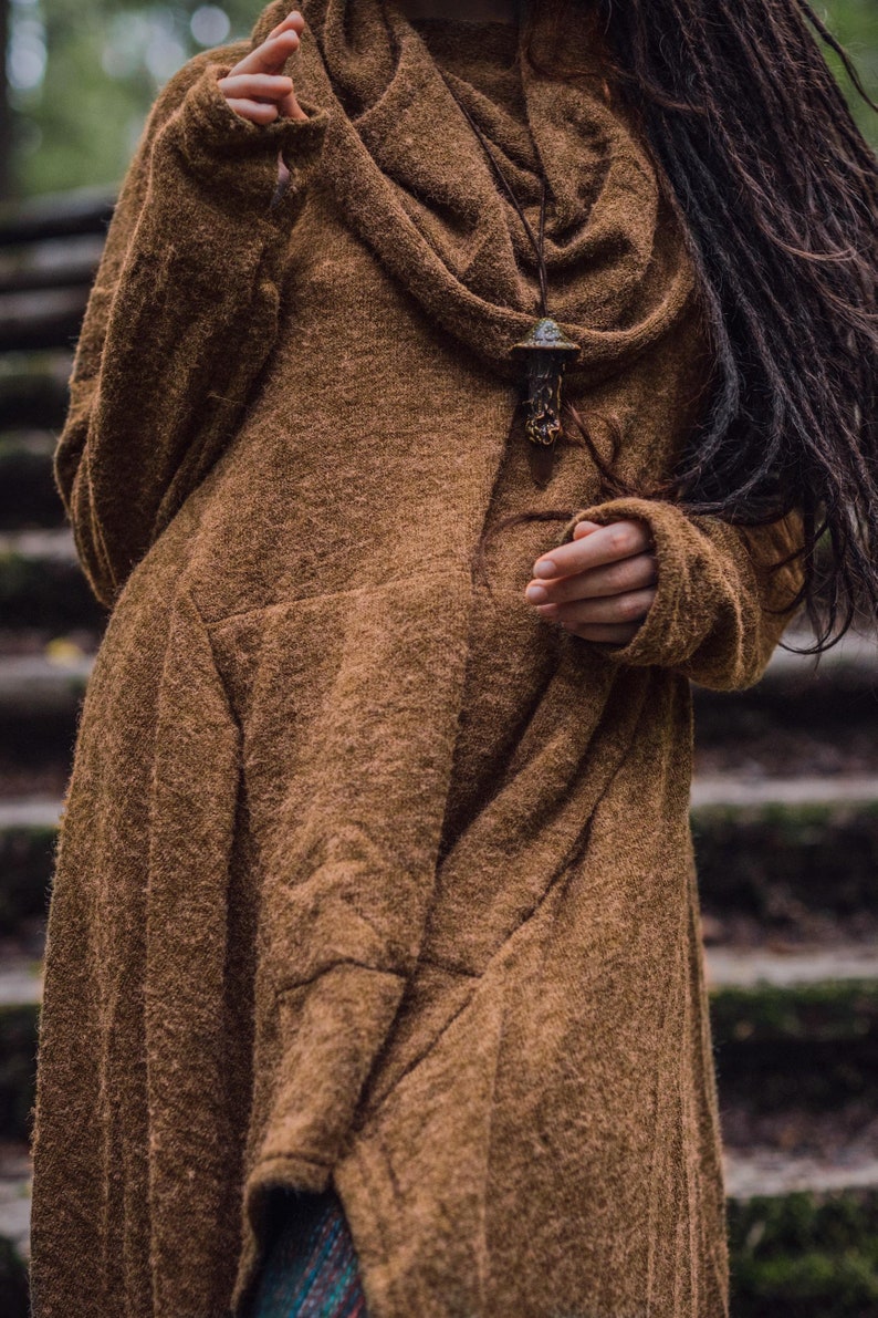 May include: A brown, long-sleeved sweater with a cowl neck and a mushroom-shaped pendant necklace.