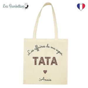 Op de afbeelding: Een beige tote bag met zwarte tekst die "Les affaires de ma super TATA" luidt met een luipaardprint. De tekst "Anais" is onder het ontwerp gedrukt.